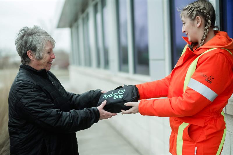 photo of a Hydro One worker handing an Emergency Preparedness kit to a customer